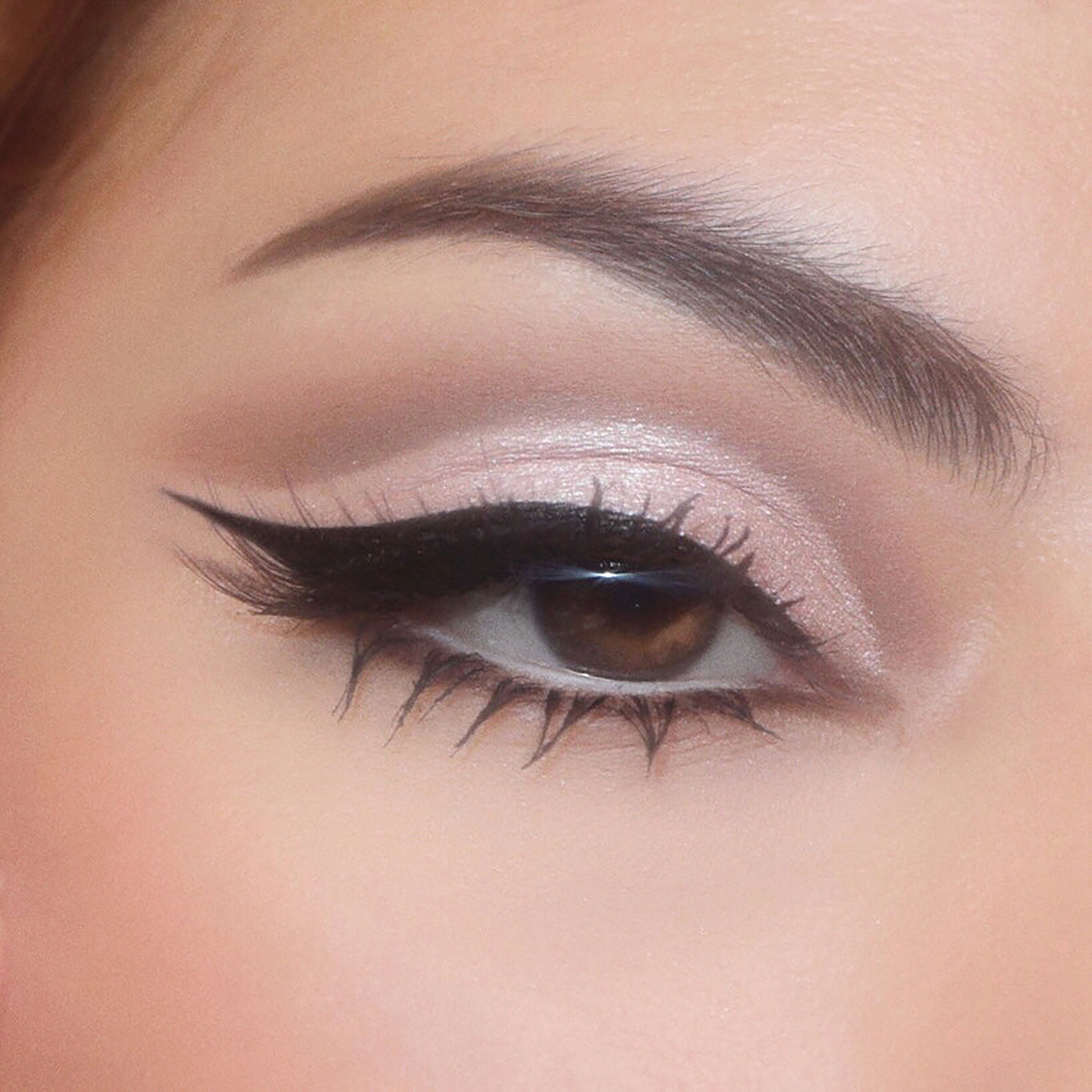 Shimmery cool taupe eyeshadow and a soft matte crease blend into a sharp black winged liner on a brown eye, showcasing The Ultimate Stunner ColourPop Shadow Palette & Brush Set with blendable neutrals and precise brush strokes for everyday glam.