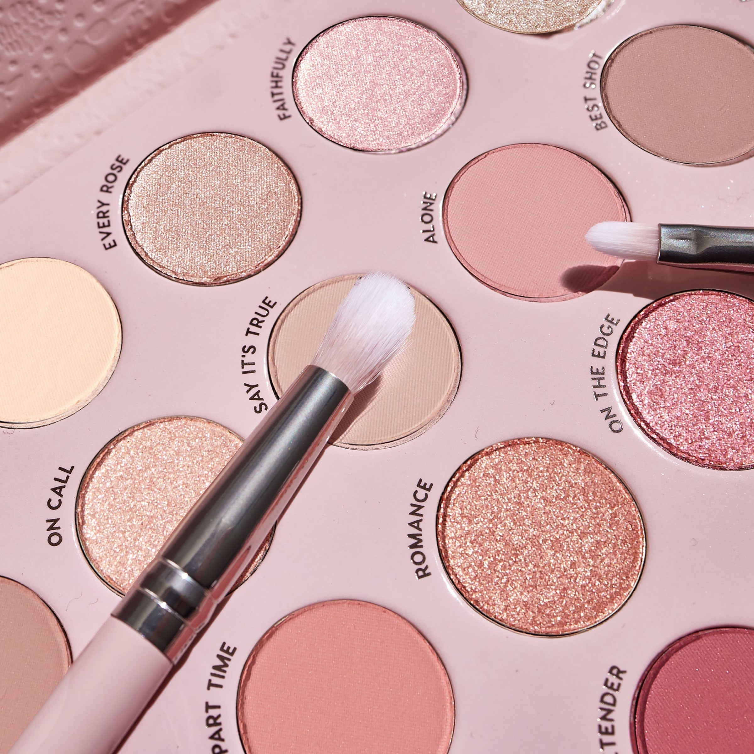 Total Smokeshow ColourPop Shadow Palette & Brush Set featuring two fluffy brushes sweeping over matte nude “Say It’s True” and shimmery rose-gold “Romance” pans, with shades like Every Rose, Alone, and On the Edge in a blush pink tray.