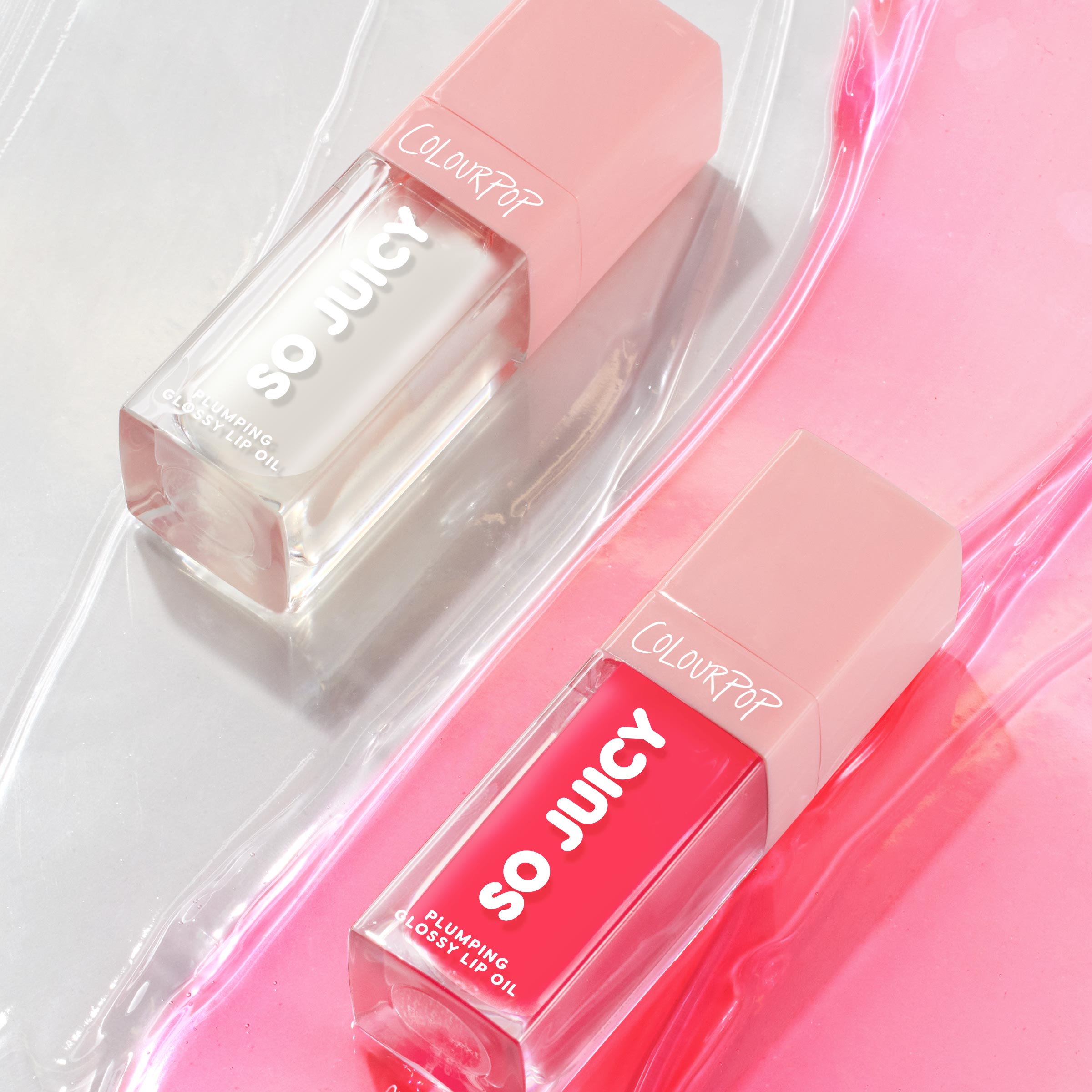 ColourPop So Juicy Lip Oil Set, Plump Perfect, showcasing two plumping glossy lip oils - one clear and one vibrant pink - in sleek rectangular tubes with blush caps, arranged diagonally on shiny pink gel swirls for a fresh, dewy look.