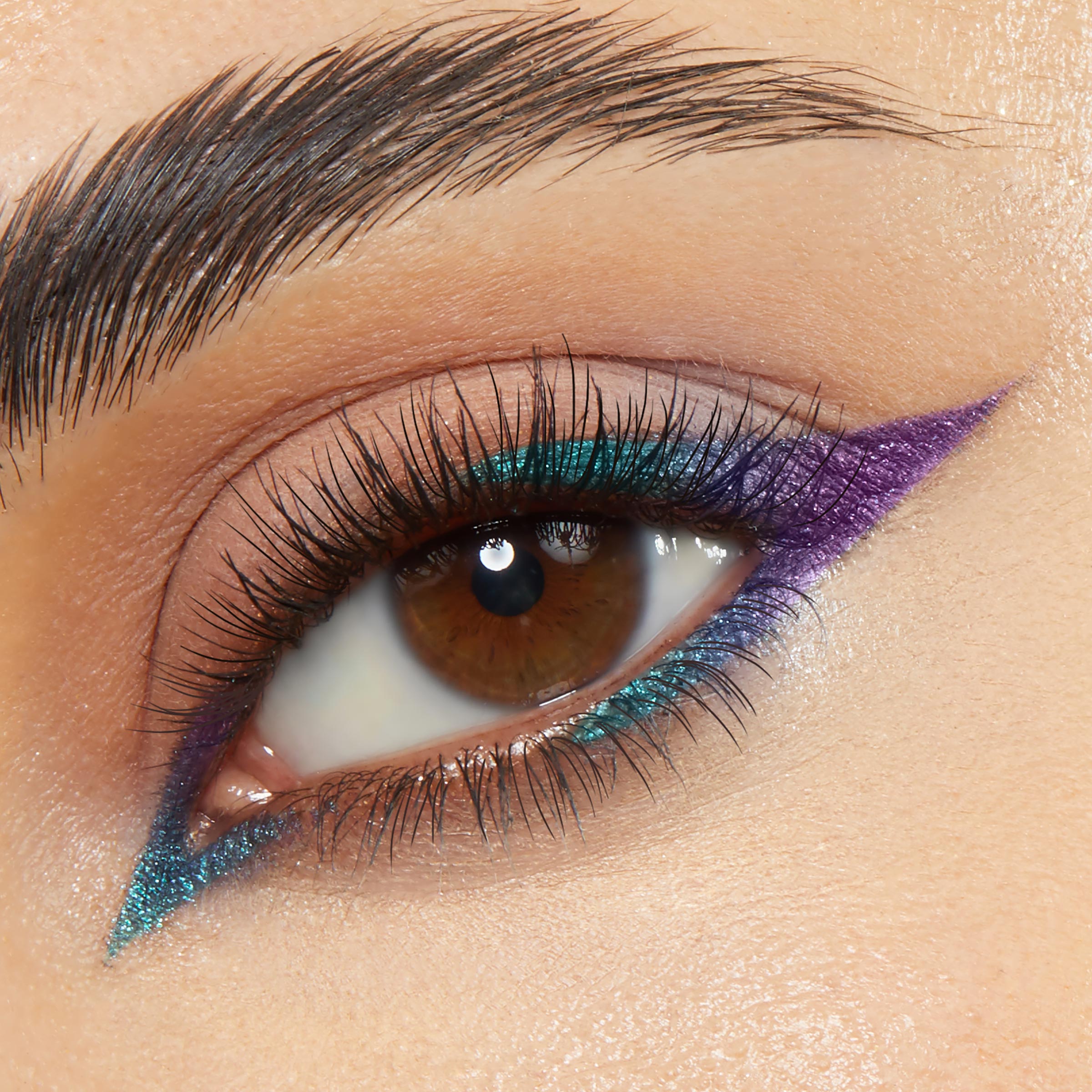 Chrome Hearted ColourPop Chrome Crème Gel Liner creates a sharp metallic teal-and-violet cat eye, with chrome shimmer sweeping the upper lid and inner corner and tracing the lower lash line, shown close-up with natural lashes and a groomed brow.