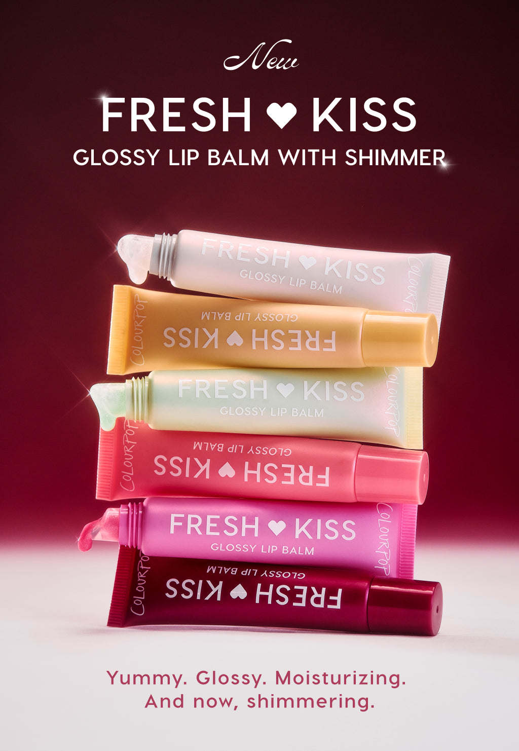 Colourpop Fresh Kiss Glossy Lip Balm with Shimmer tubes stacked in pink, coral, mint, gold and pearl shades on a glowing burgundy background, highlighting the new shimmering, moisturizing Colourpop lip balm collection.