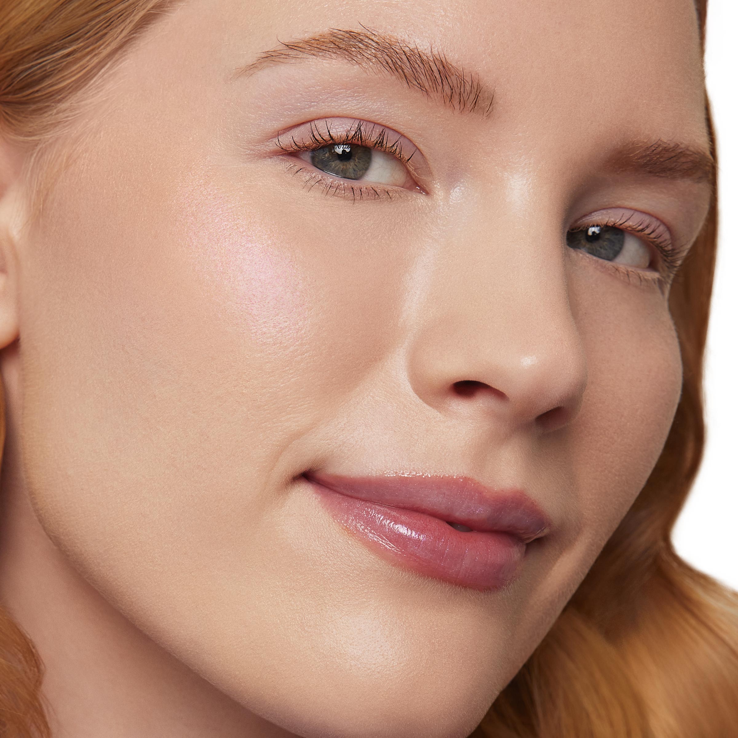 Cheekbone glows with an iridescent pink sheen as I See the Light ColourPop Liquid Highlighter is applied to the high points, showcasing a dewy, natural finish on a model’s face in a studio close-up.