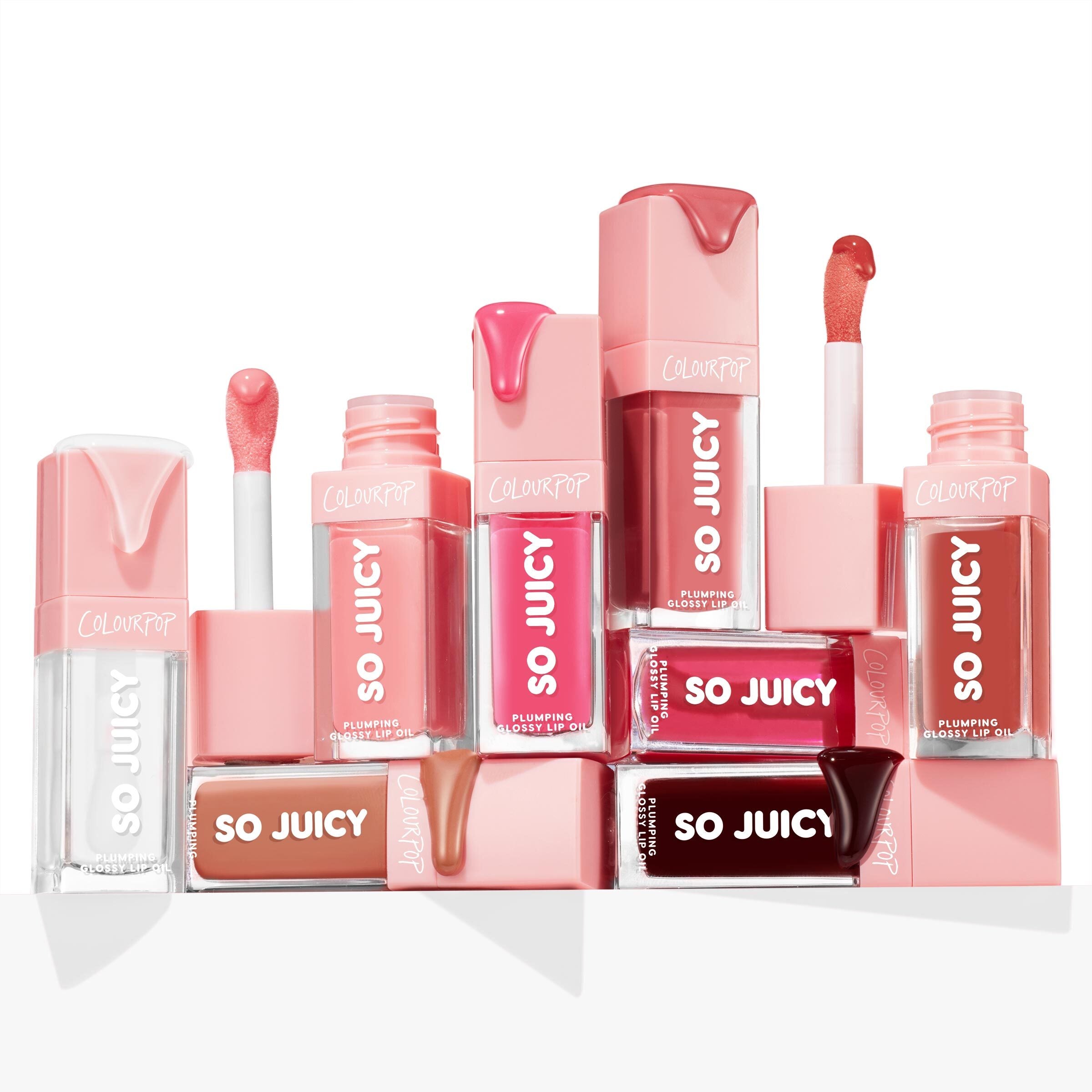 ColourPop So Juicy Lip Oil Set 100% Juicy displayed in a stacked layout, tubes and open wands showing glossy drips in clear, nude, pink, red, and deep berry shades, highlighting plumping, high-shine formula in pink-capped packaging on a white backdrop.