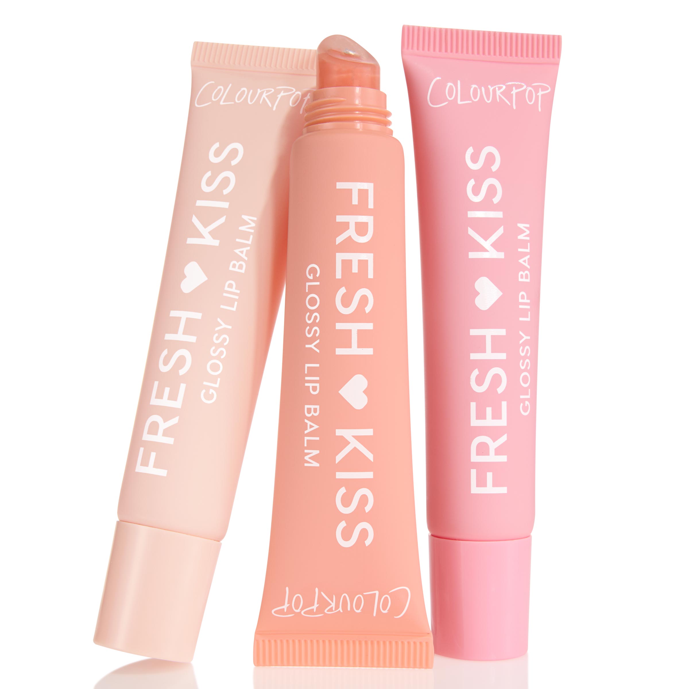 Pretty in Pastels ColourPop Glossy Lip Balm Trio showcases three Fresh Kiss glossy lip balms - soft pink, peach, and blush - with the center tube uncapped to show a slanted applicator, arranged upright on a white background.