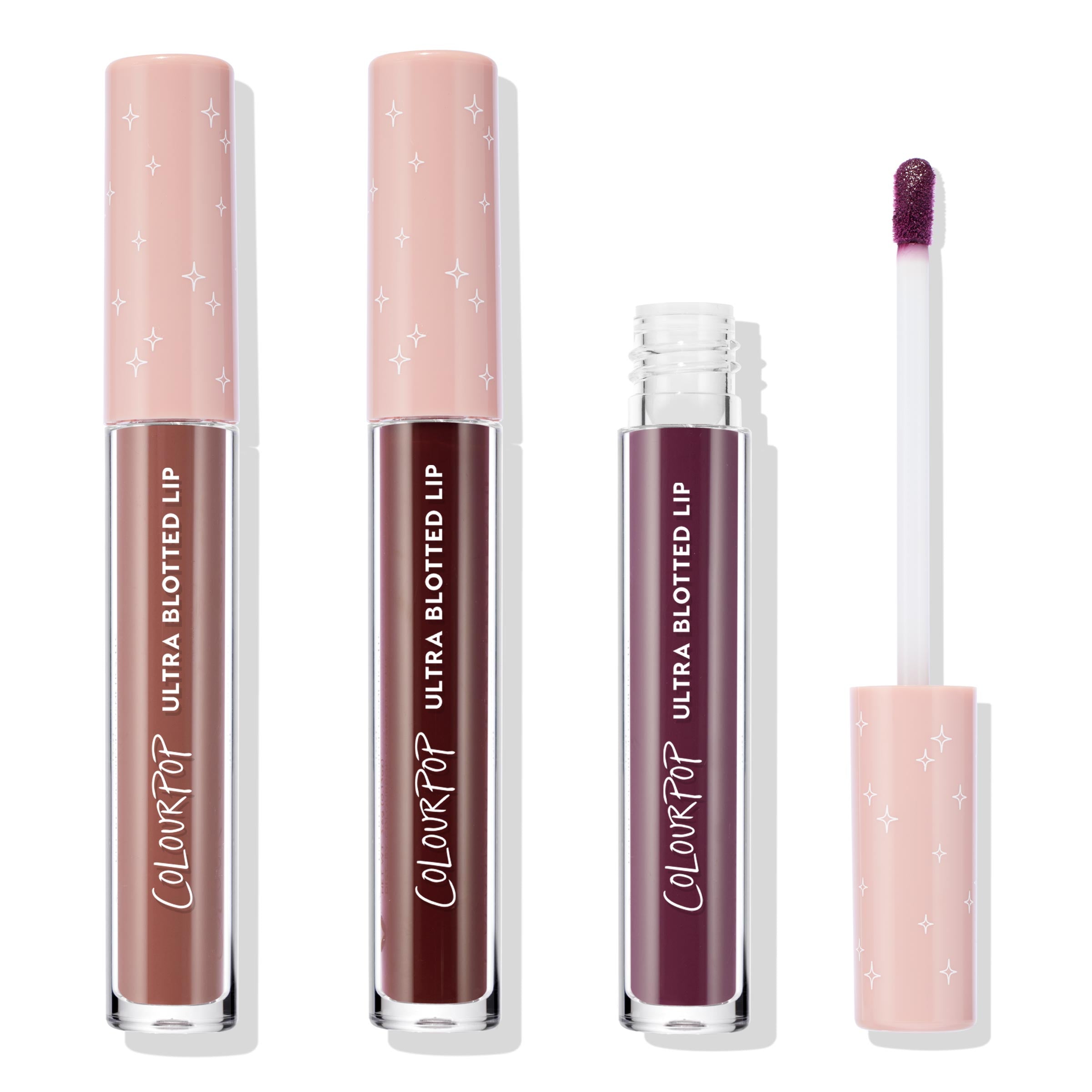 ColourPop Ultra Blotted Lip Edgy Vibes trio stands upright with one tube opened to show a doe‑foot applicator, on a white background; pink starry caps top nude rose, deep burgundy, and plum shades.