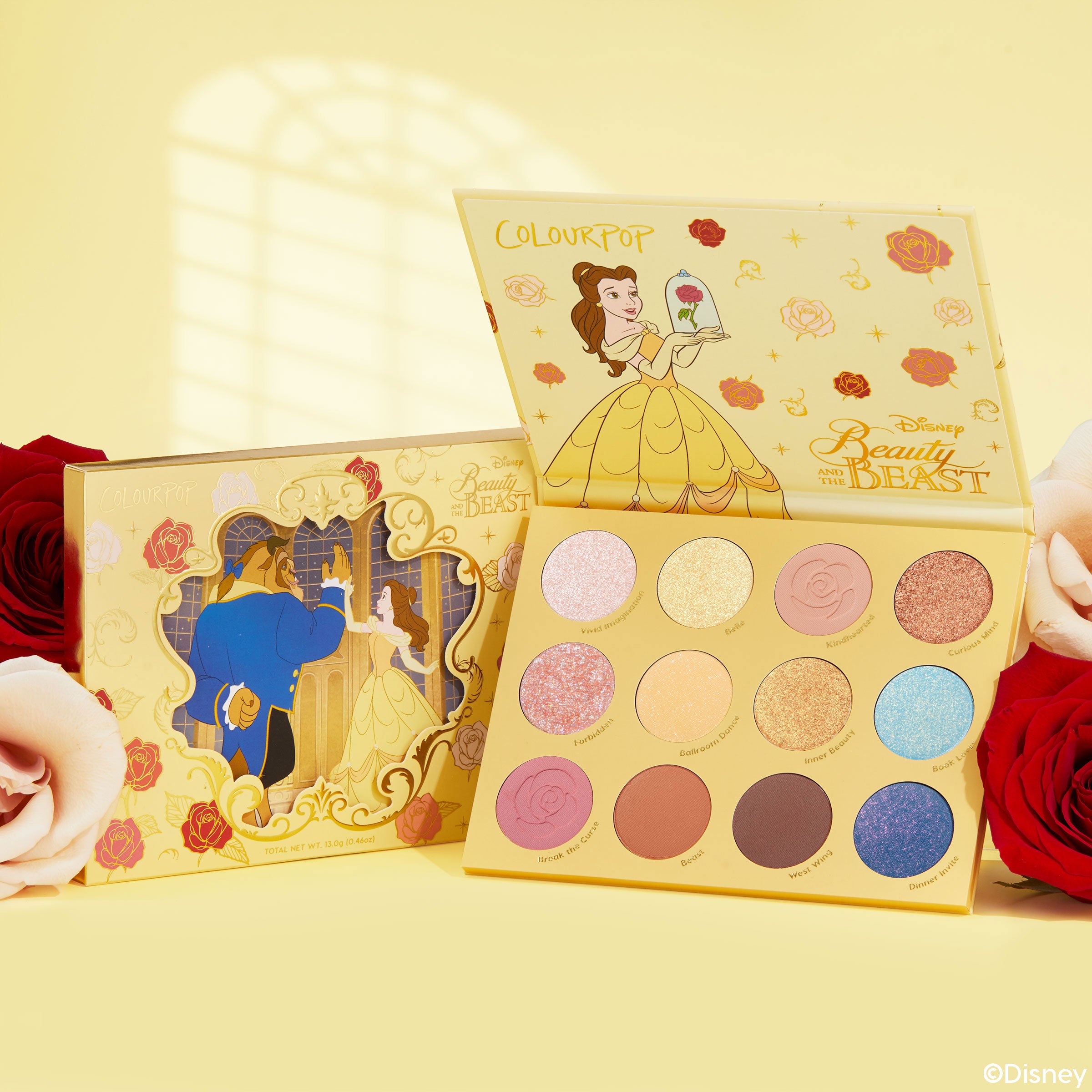 ColourPop Shadow Palette Beauty and the Beast opens to show 12 pans in pinks, golds, corals, and blues with matte and glitter finishes, Belle art on a yellow case, with matching box and roses on a soft yellow background.