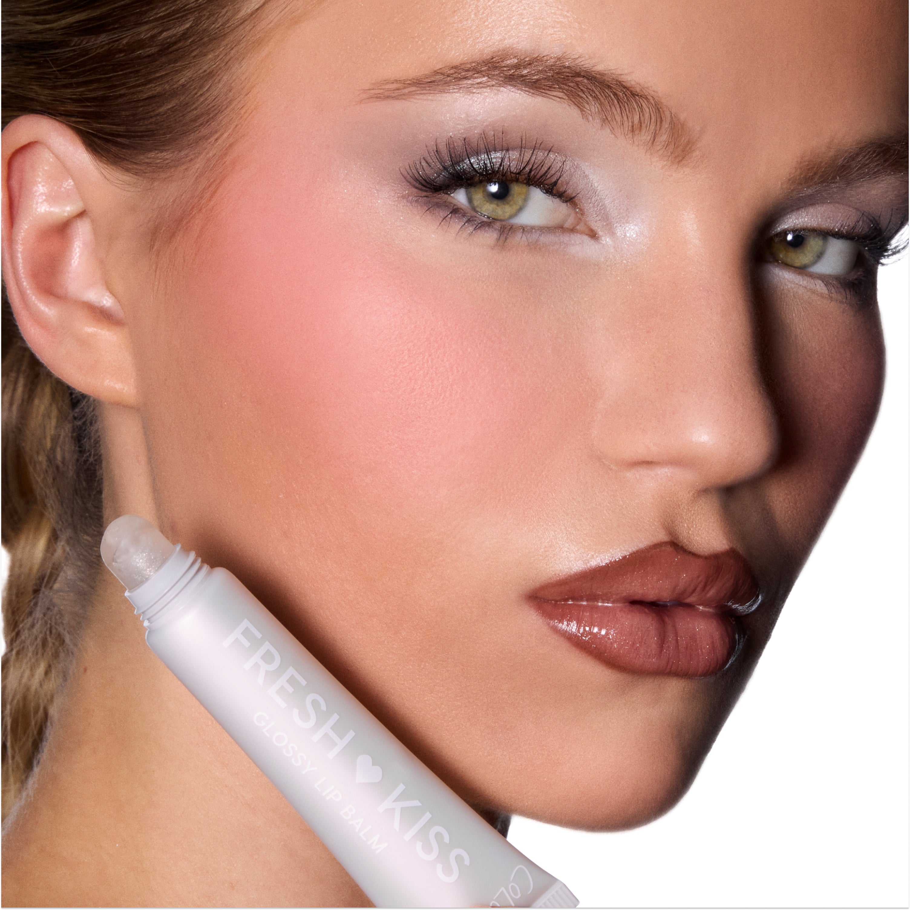 Model wears Colourpop Buttery Pancakes Fresh Kiss Glossy Balm, showing high-shine nude lips while holding the clear tube of Lip Gloss & Lip Oil hybrid against her cheek on a clean white background.