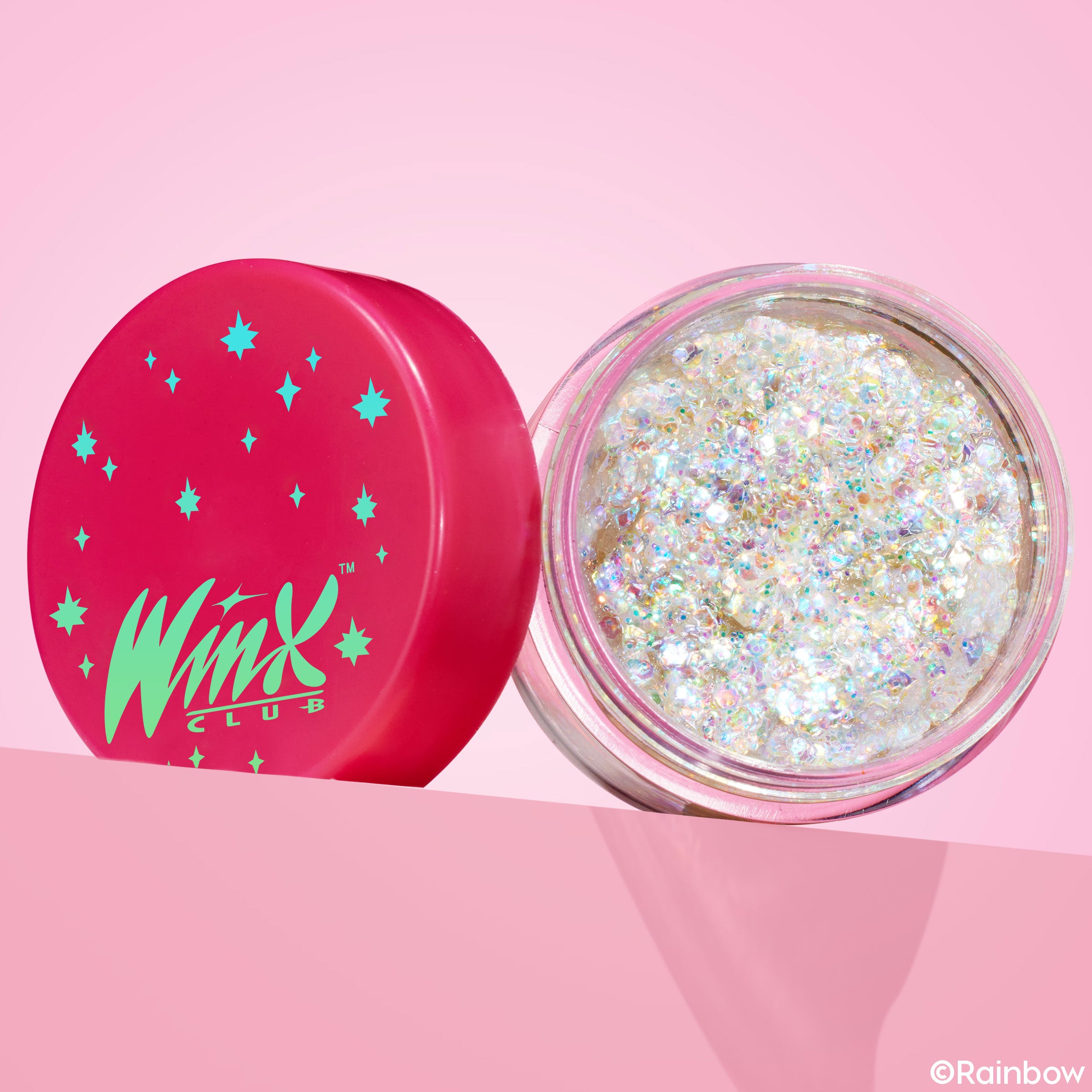 Enchantix ColourPop Glitter Gel jar showing iridescent, chunky opal glitter in a clear pot, lid off to the side; hot-pink cap with teal stars and Winx Club logo, set on a pink gradient background for a bold, sparkly makeup look.