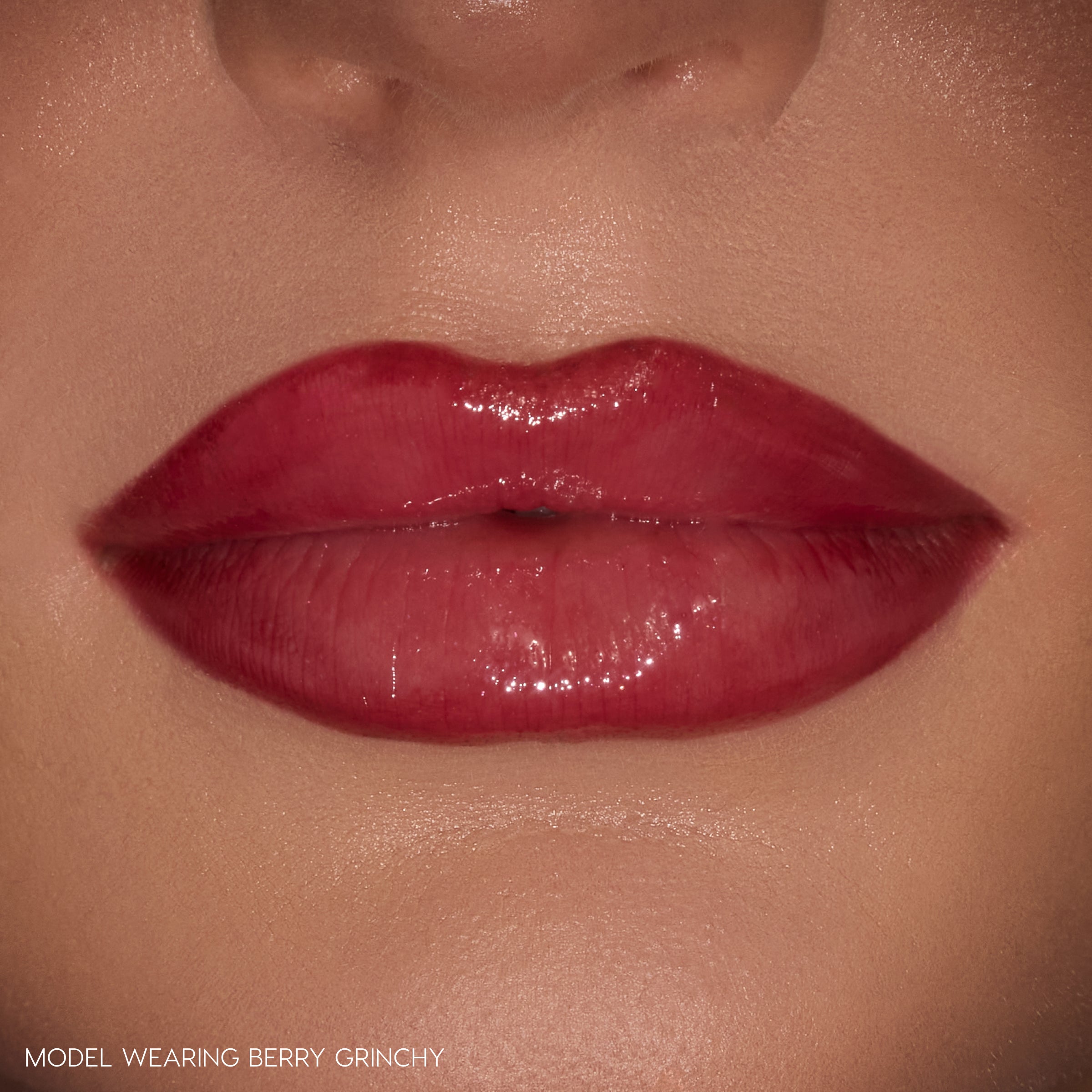 Glossy berry-stained lips wearing ColourPop Berry Grinchy So Juicy Plumping Gloss Stick, delivering plumped shine and a sheer berry tint in a tight close-up against natural skin.