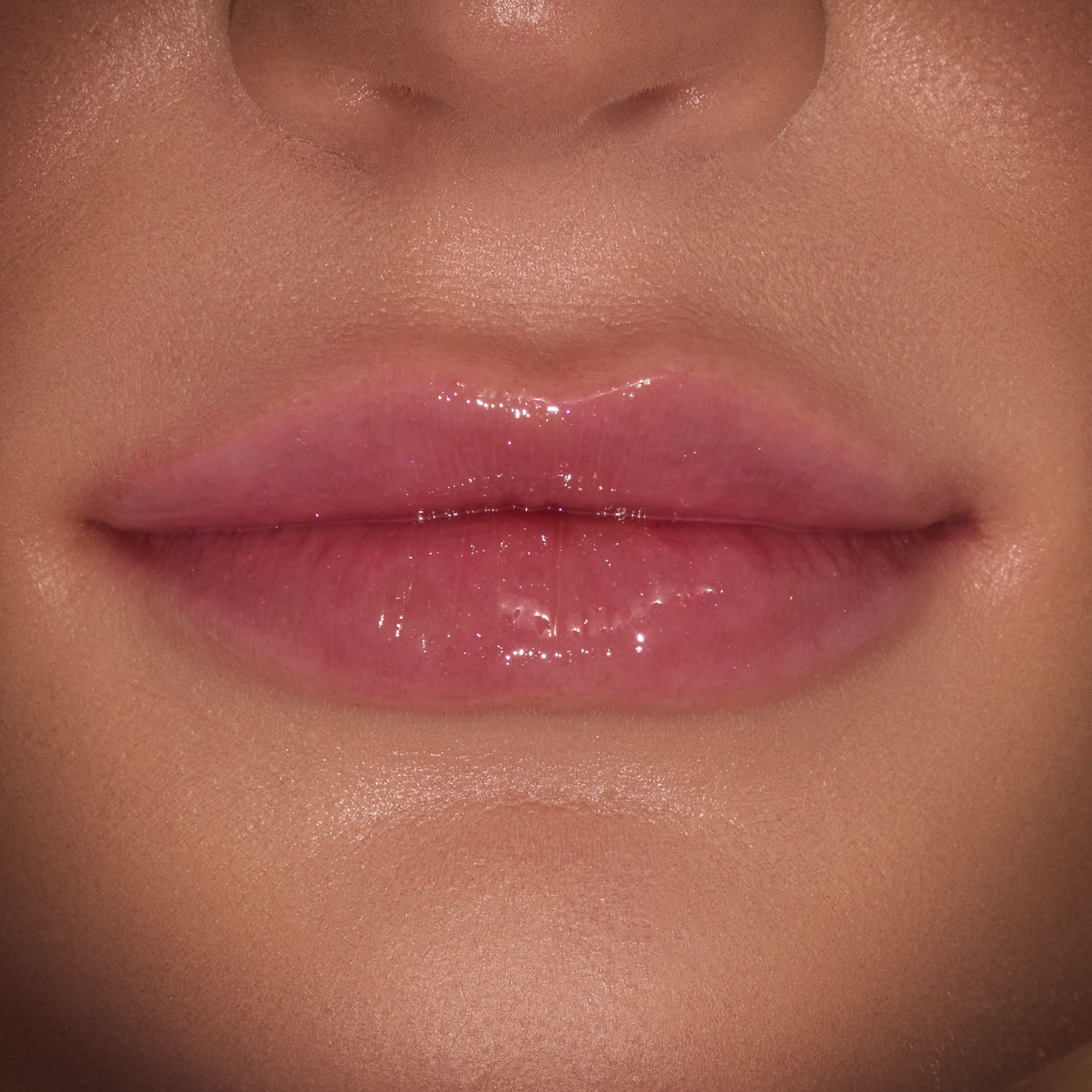 Glossy lips wearing a sheer pink, high-shine finish from the ColourPop Merry Grinchmas Swirl Lip Gloss Kit, shown in a tight close-up to highlight the glassy sheen and smooth texture.