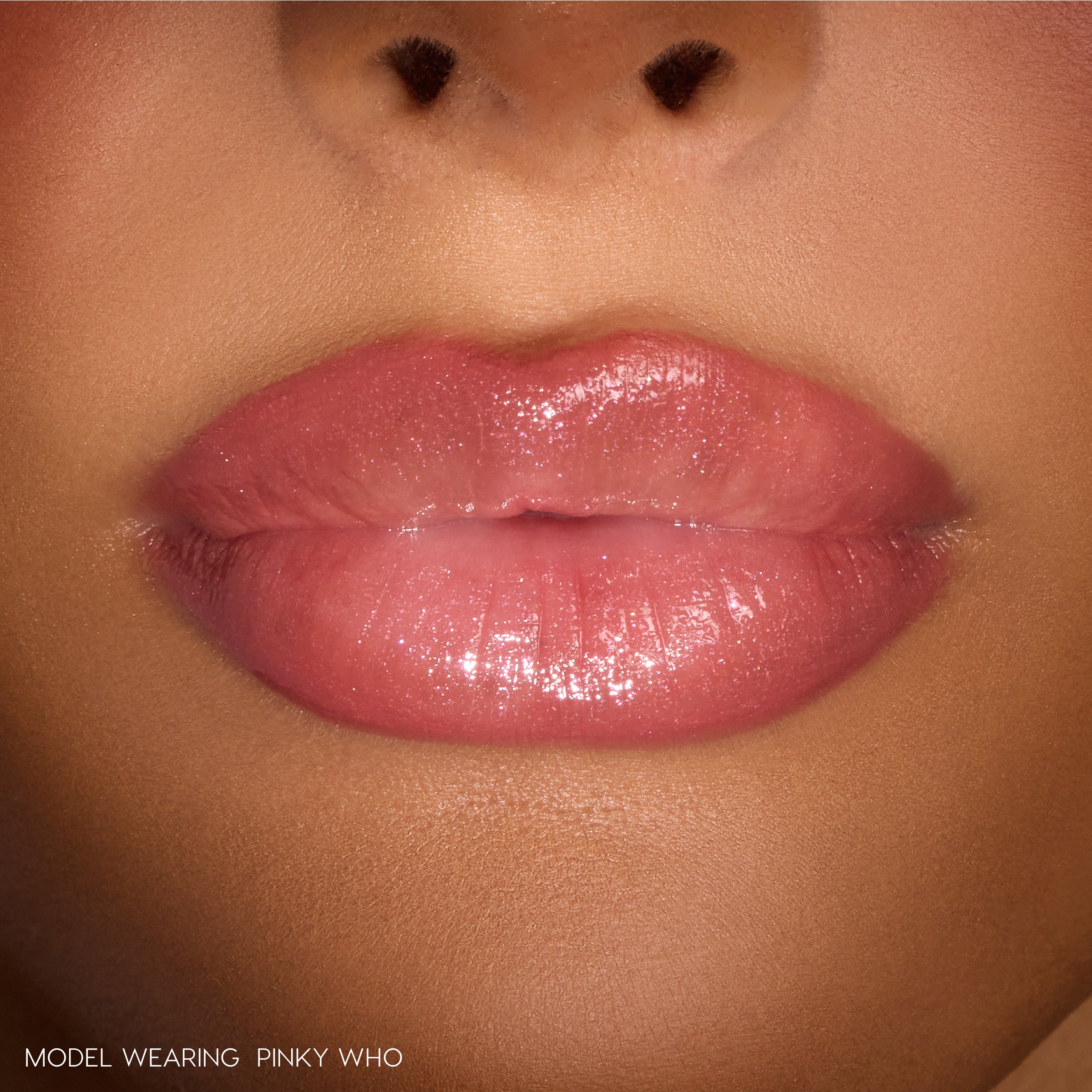 Close-up lips wearing ColourPop So Juicy Plumping Gloss Stick, shade Pinky Who, showing a cushy, plumped look with sheer medium‑pink, high‑shine finish under studio lighting.
