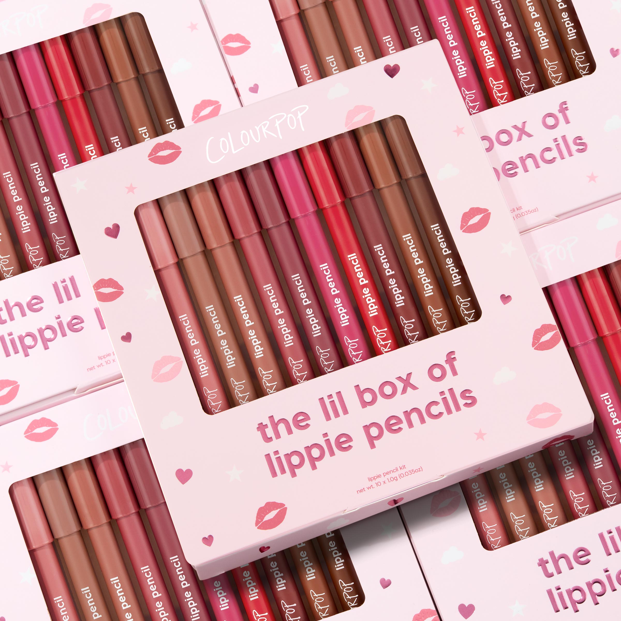 ColourPop Lippie Pencil set presenting The Lil Box of Lippie Pencils, a multi-shade lip liner kit displayed in a pink box with a clear window; pencils in nude, pink, and red tones lined up, with stacked kiss-print packaging in the background.