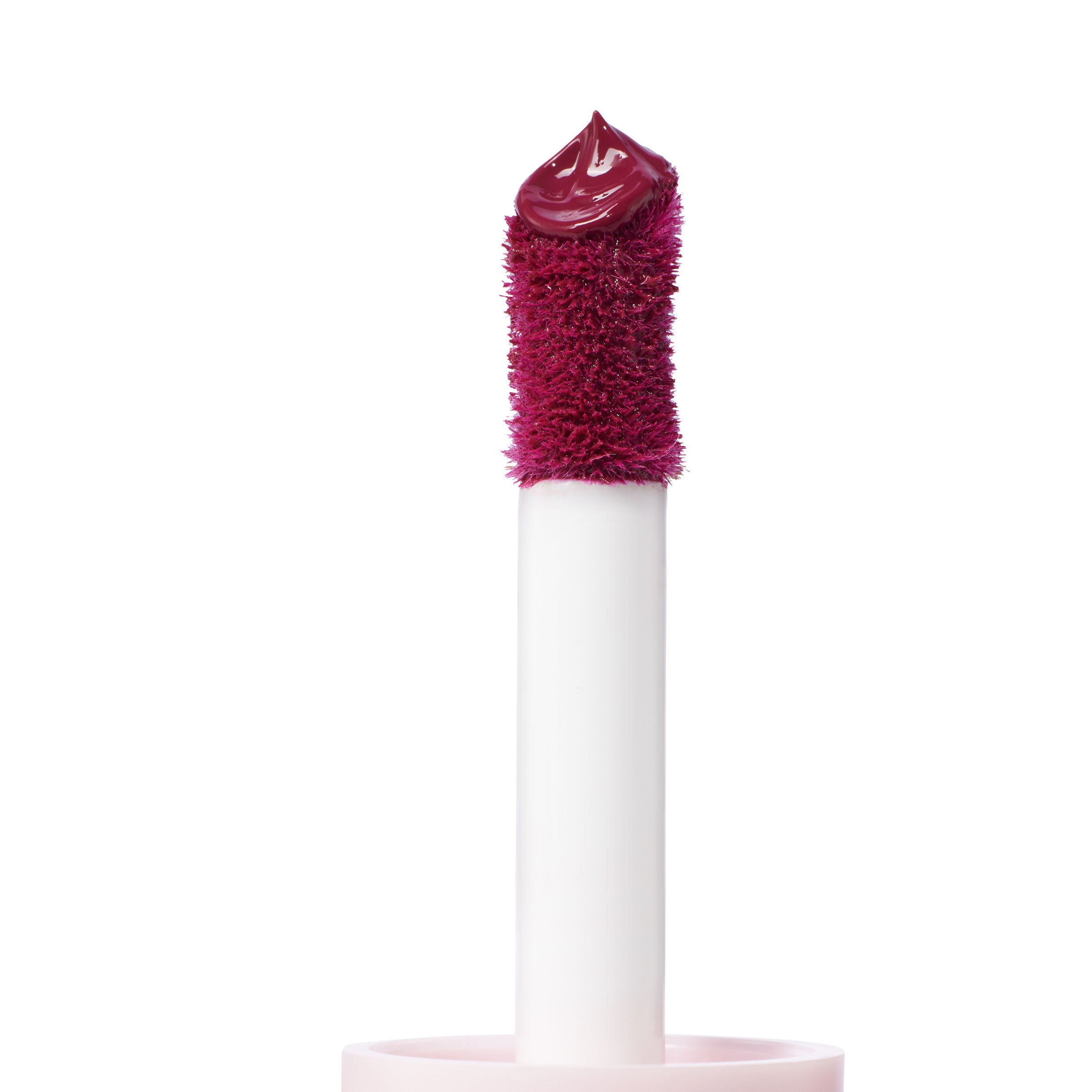 Doe-foot applicator deposits a glossy, deep berry dollop of Royal Flush ColourPop Liquid Blush, shown in close-up on a white background, highlighting the plush wand and precise tip for smooth, buildable cheek color.