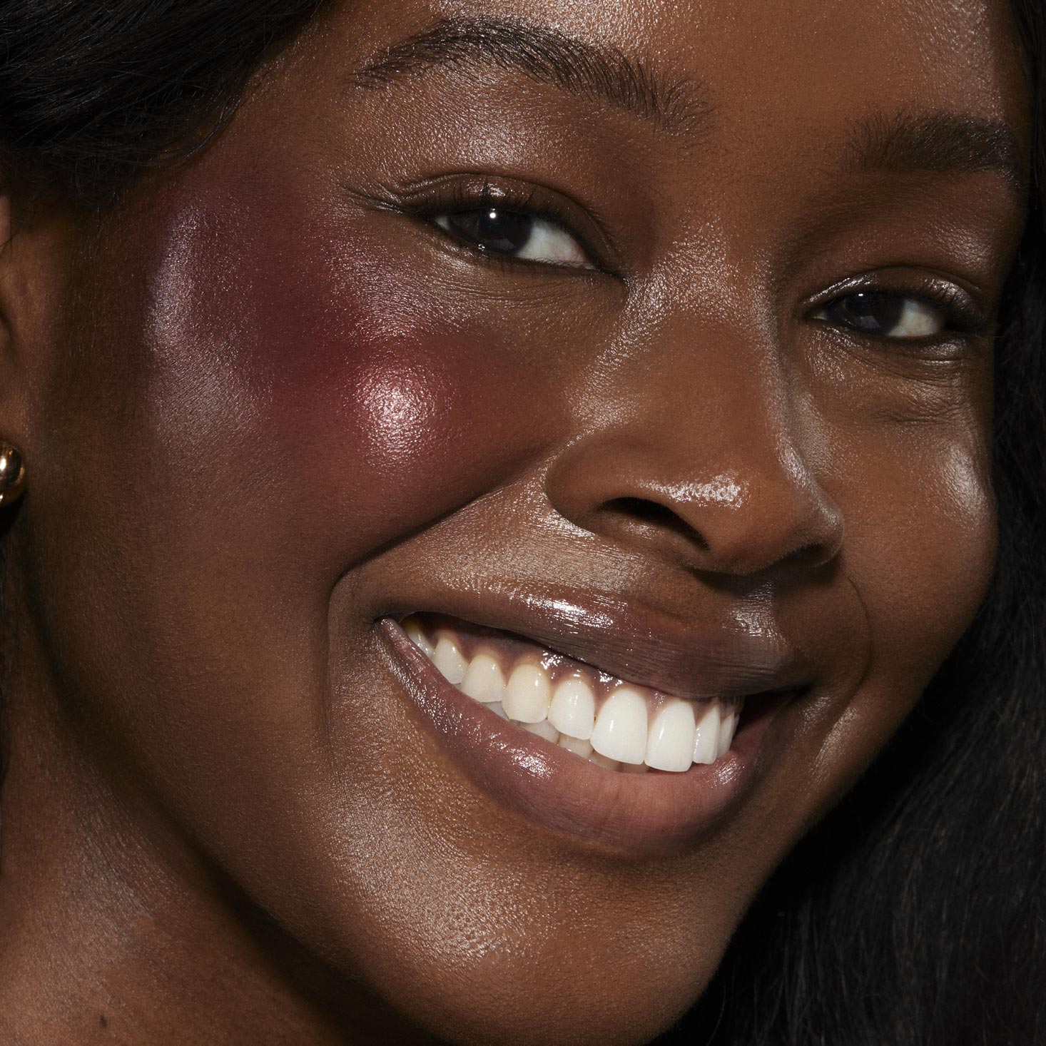 Wine n' Dine ColourPop Liquid Blush creating a dewy berry glow on a smiling model’s cheeks in a close-up, highlighting glossy skin and a radiant sheen for everyday glam.