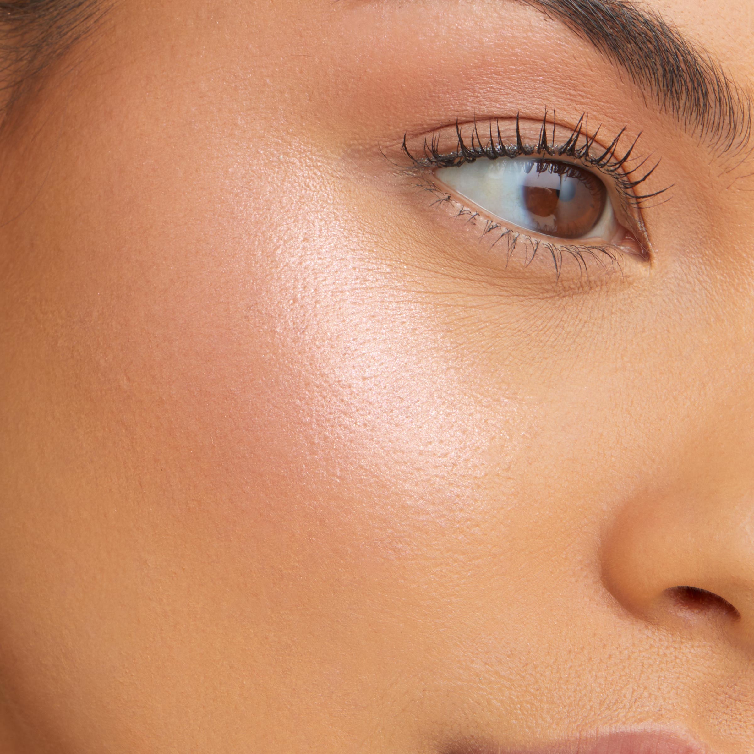 ColourPop Super Shock Highlighter in Magix Gem illuminating a model’s cheekbone, creating a soft pink‑pearl sheen with a smooth, dewy finish; close-up shows seamless blend from eye area to cheek for a radiant glow.