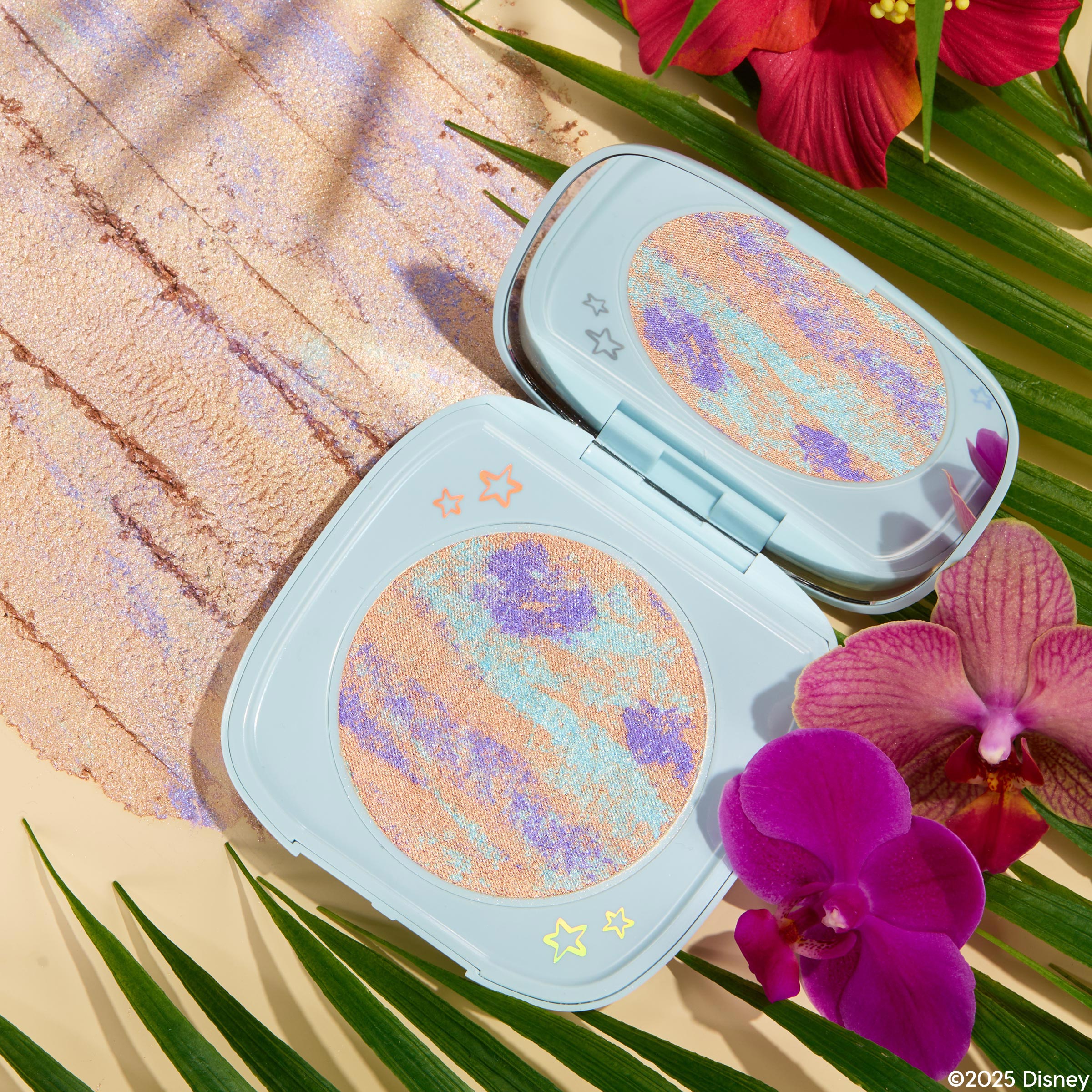 Ohana ColourPop Super Shock Highlighter compact opens to reveal a marbled peach, lavender, and aqua pan in a pastel blue case with star accents, shown with a shimmery swatch beside palm leaves, orchids, and hibiscus.