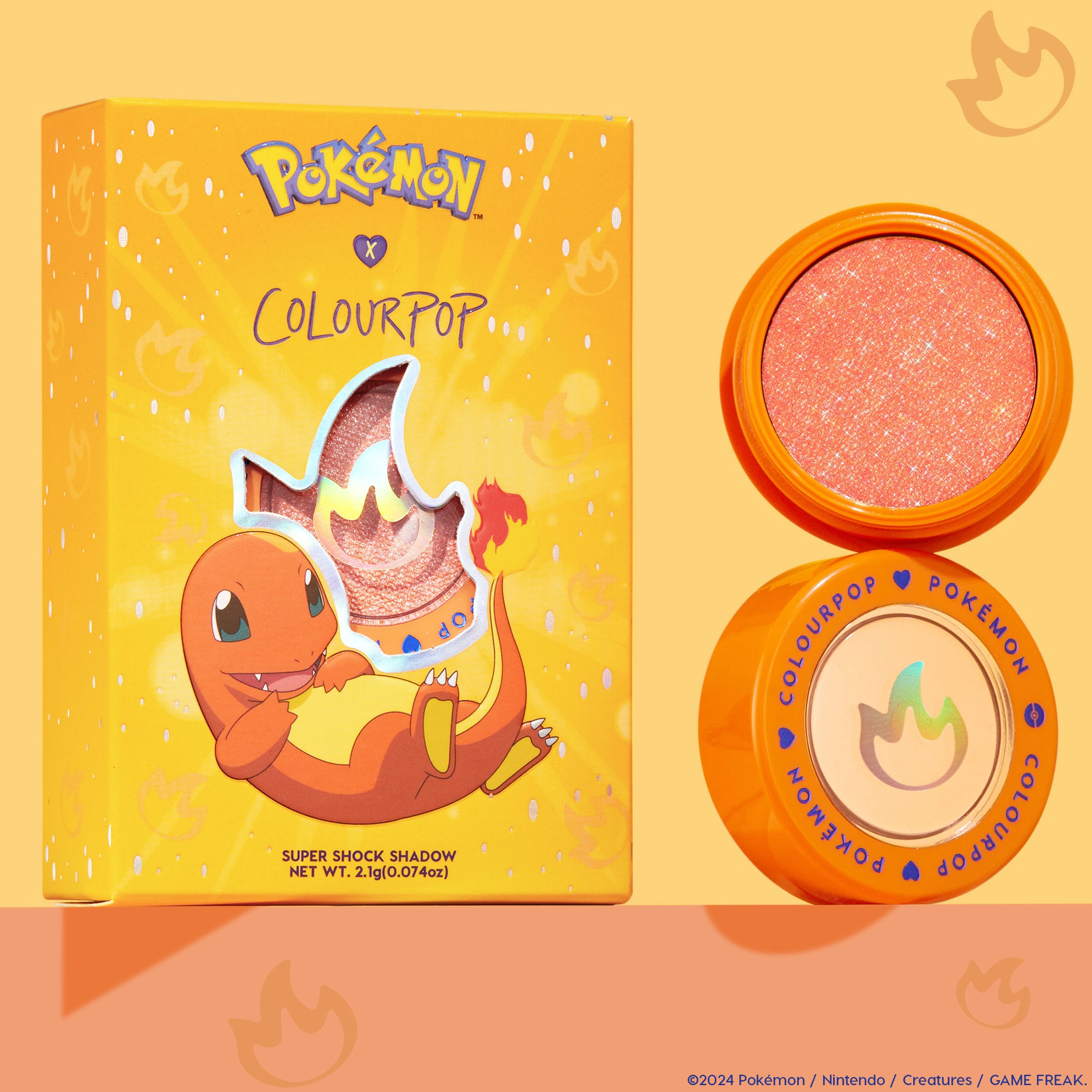 ColourPop Super Shock Shadow in Flamethrower, a sparkly peach‑orange metallic eyeshadow, shown open in an orange pot beside the Pokémon x ColourPop box featuring Charmander and a flame cutout, on a warm peach background.