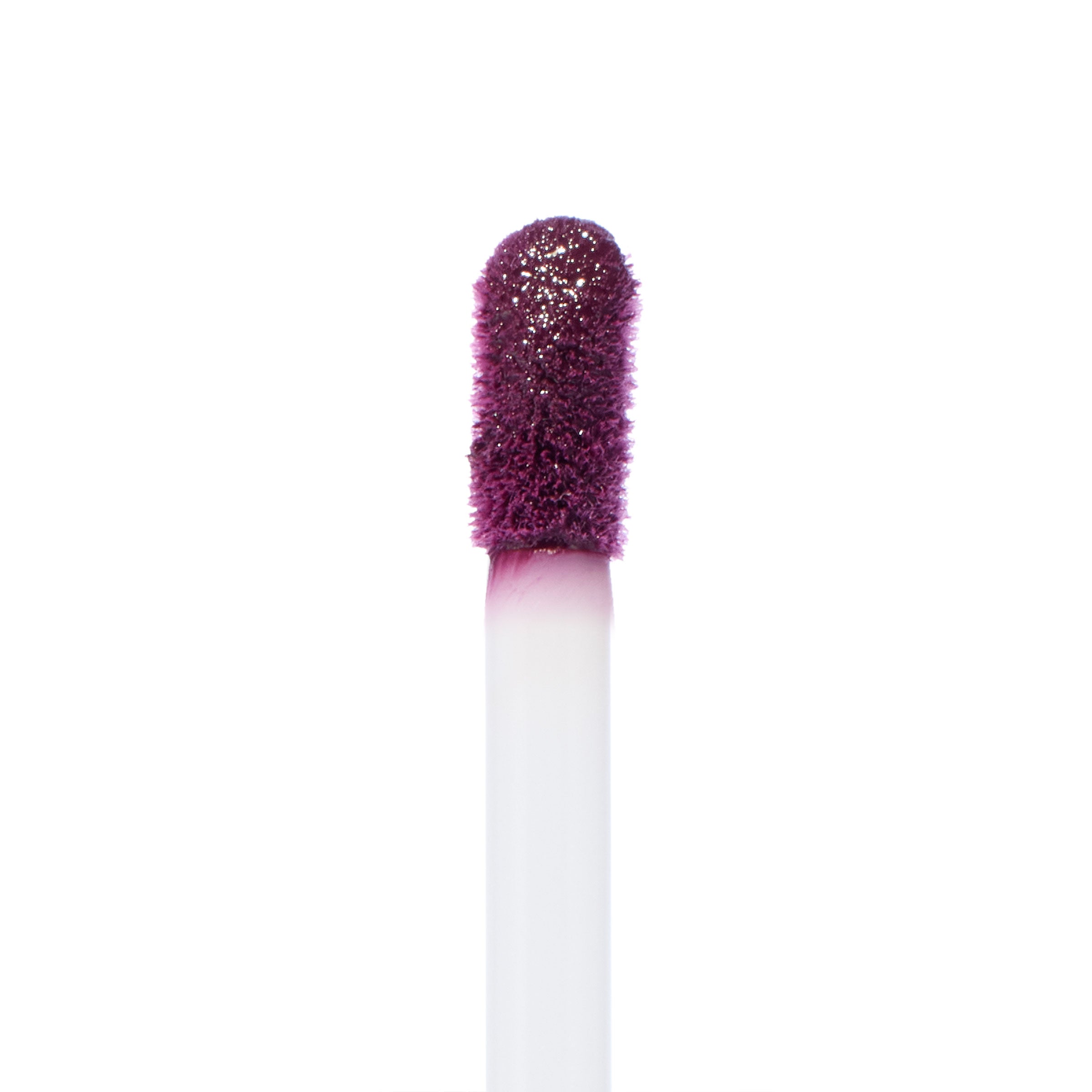 Doe-foot applicator coated in So Vintage, a deep berry-plum ColourPop Ultra Blotted Lip, lifting pigment with a soft, fuzzy tip against a white background, highlighting the saturated color for precise application.