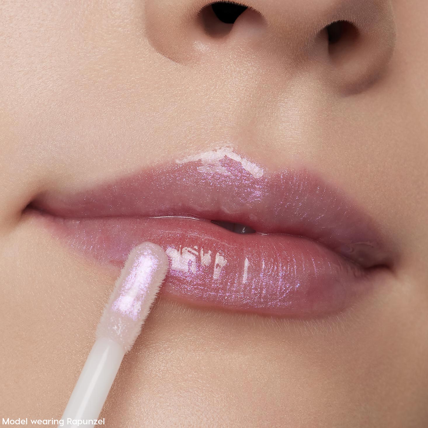 Doe-foot applicator sweeping Rapunzel ColourPop Ultra Glossy Lip onto close-up lips, revealing a glassy, high-shine finish with sheer pink-lilac iridescent shimmer.