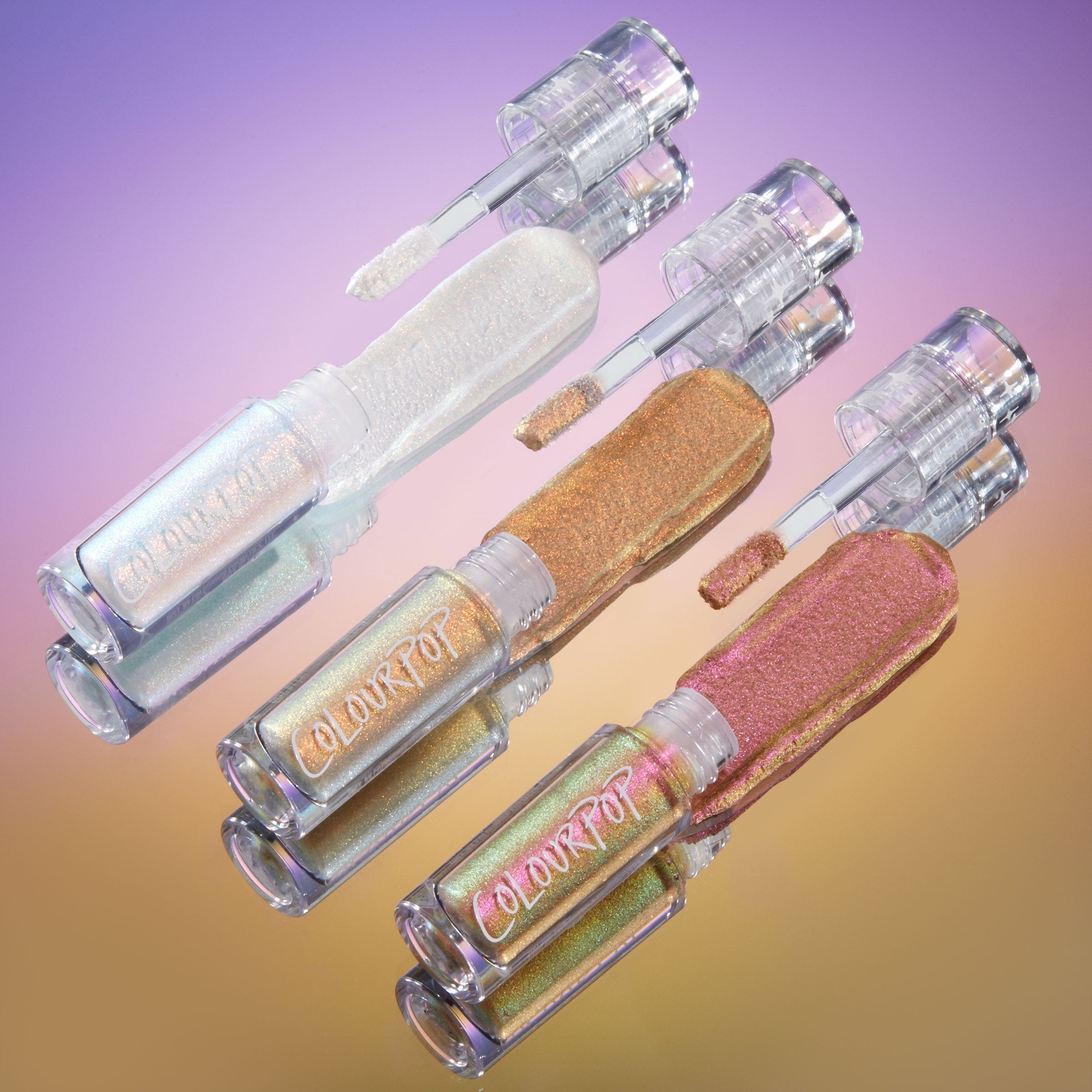 Vibe Shift ColourPop Chrome Liquid Shadow trio swipes pearly opal, bronze-gold, and pink‑green multichrome shades with open doe‑foot wands beside clear ColourPop‑branded tubes, arranged diagonally on a purple-to-gold gradient backdrop.