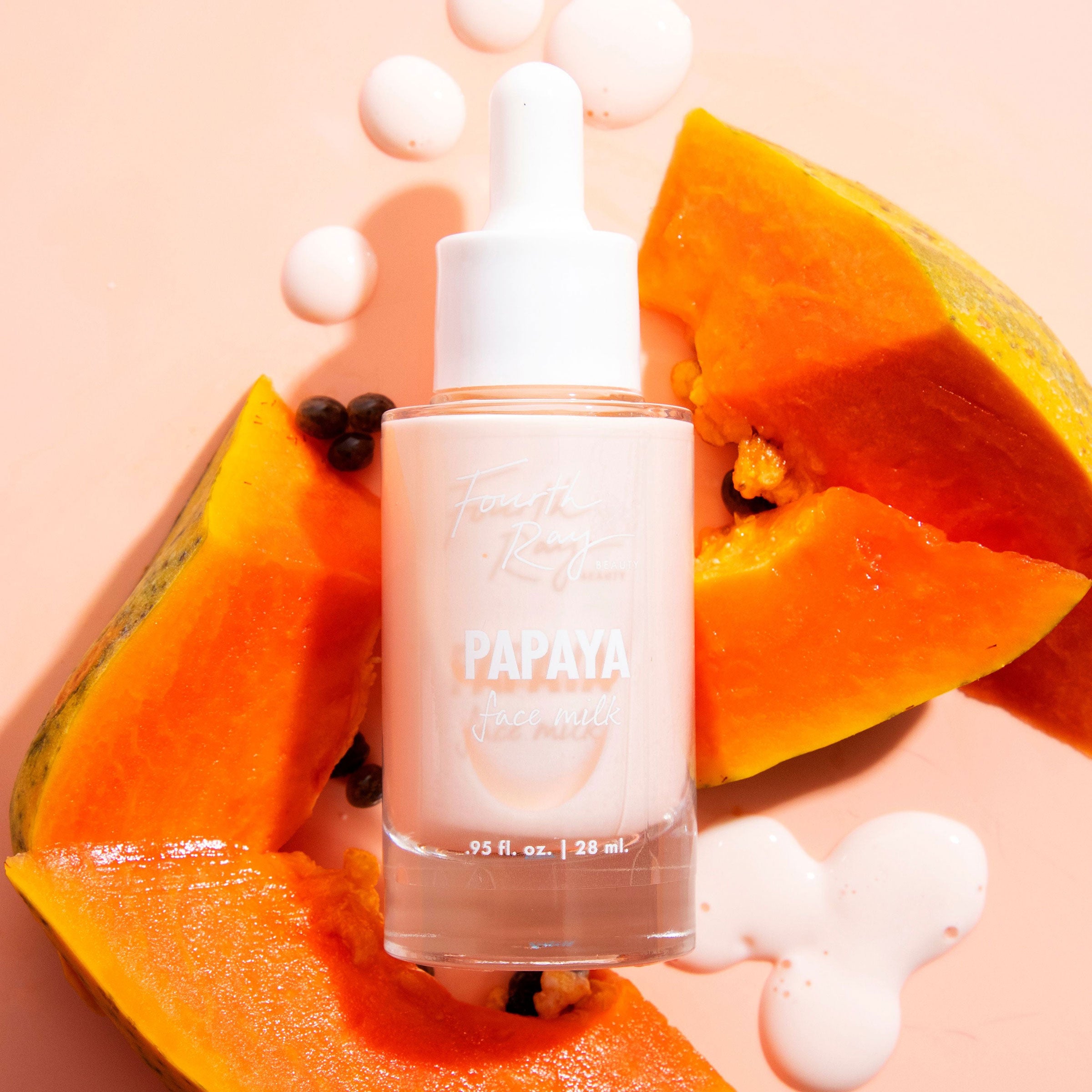 Fourth Ray Beauty Papaya Face Milk bottle standing upright with white dropper, labeled 0.95 fl oz/28 ml, surrounded by bright orange papaya wedges, seeds, and milky drops on a peach backdrop, highlighting this hydrating ColourPop Face Milk.