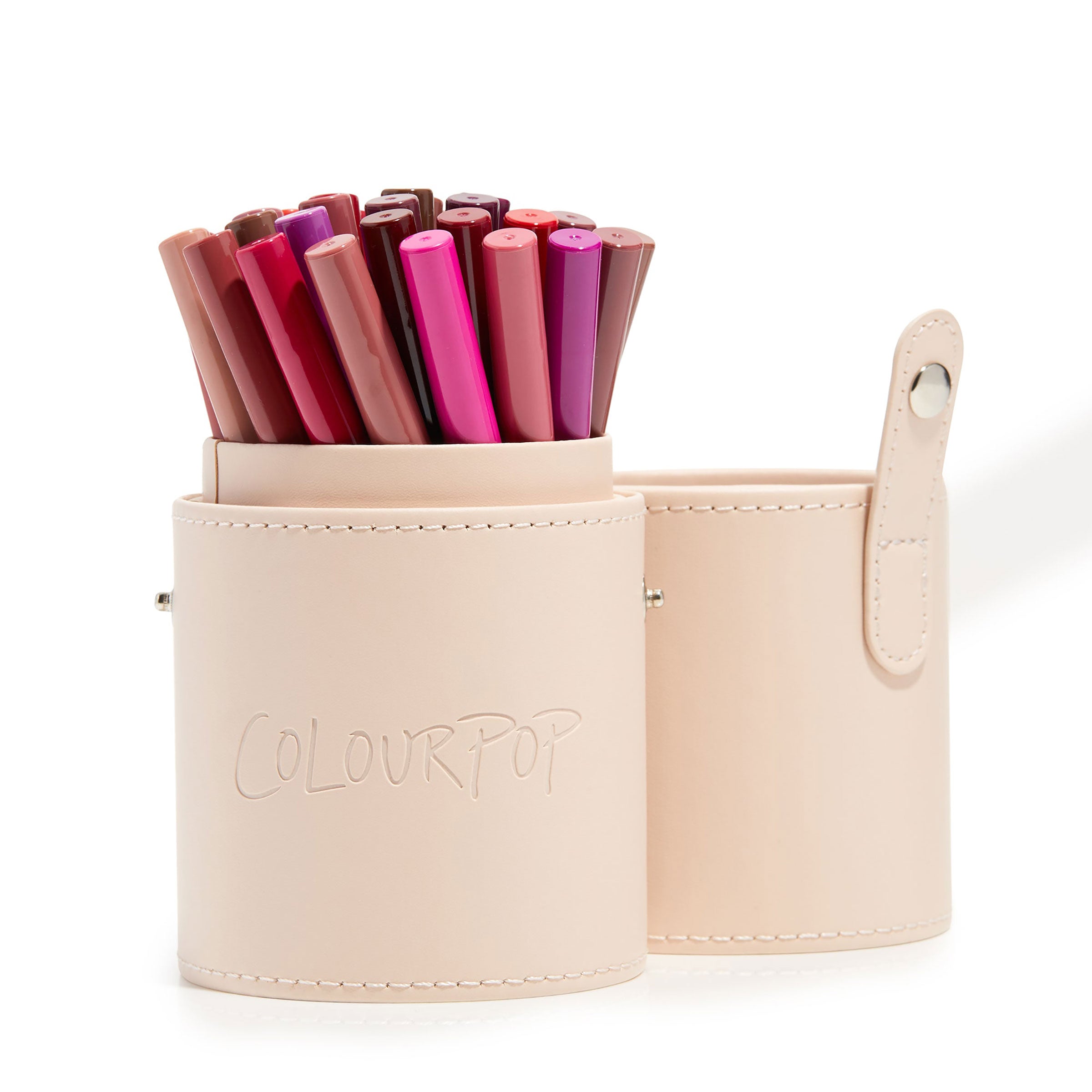 ColourPop Small Stash Cup holding assorted pink and nude makeup pencils, a two-piece cylindrical brush holder with snap strap and embossed logo in pale beige, ideal makeup tools & accessories organizer on a white background.