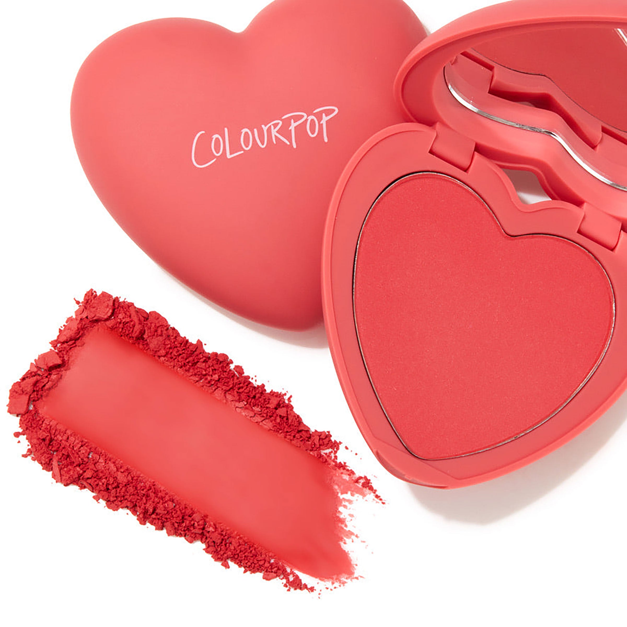 Heart-shaped compact of ColourPop Pressed Powder Blush, 4ever Yours, opened to a coral-pink pan with mirror, alongside a rich swatch and crushed powder showing pigment and texture on a clean white background.
